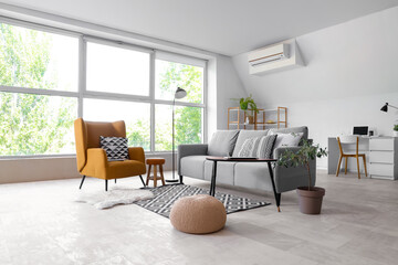 Interior of light living room with grey sofa, table and armchair