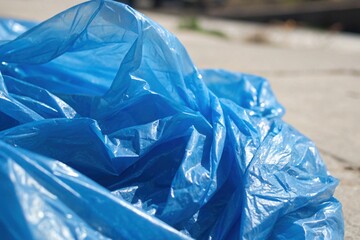 Close-up of a blue plastic wrap dustbin on a sidewalk. A dustbin on the street for recycling