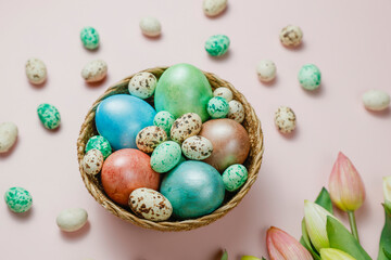 Easter eggsin basket on pink background with tulips.