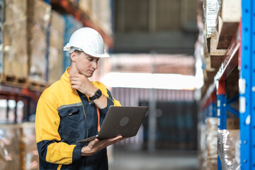 Obraz premium White employee holding and looking at laptop with serious emotion, working in warehouse, worker in yellow colar pointing and looking at product on shelf in logistic industry.