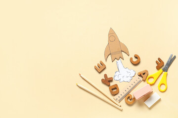 Cardboard rocket with smoke and different school stationery on beige background