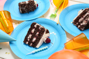 Paper plates with tasty birthday cake, cups and decor on light wooden table, closeup