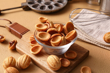 Wooden board with bowl of tasty walnut shaped cookies on color table