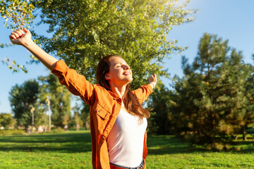 Happy young woman welcomes nature with open arms. Happiness and wellbeing.