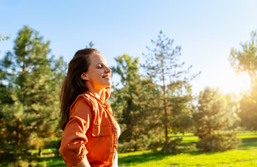 Young woman enjoying walking outdoors in greenery area in summer