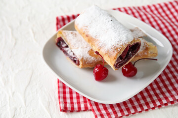 Plate with sweet cherry strudel on white background
