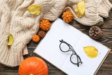 Composition with book, eyeglasses, sweater and autumn decor on wooden background