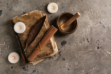 Old book, incense sticks, candles and Tibetan singing bowl on grey background