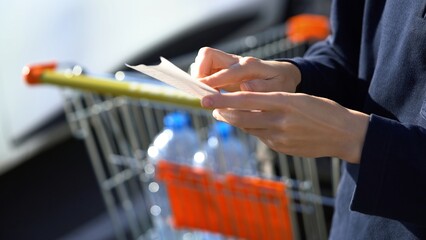Customer hold receipt bill. Buyer checks. Shopping cart on background. Paper receipt on shopping...