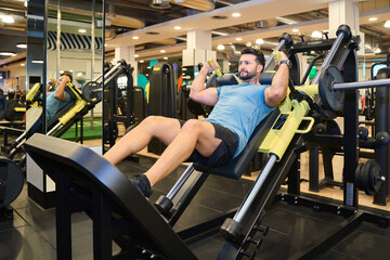Man performing leg press exercise in modern gym