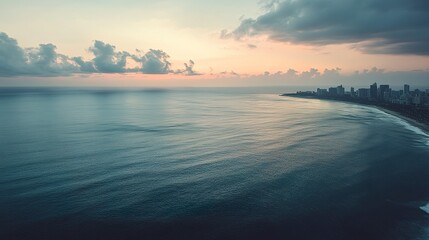 Fototapeta premium Quiet bay with calm waves, dramatic cityscape on the horizon, soft cloud cover, aerial perspective, muted twilight hues. 