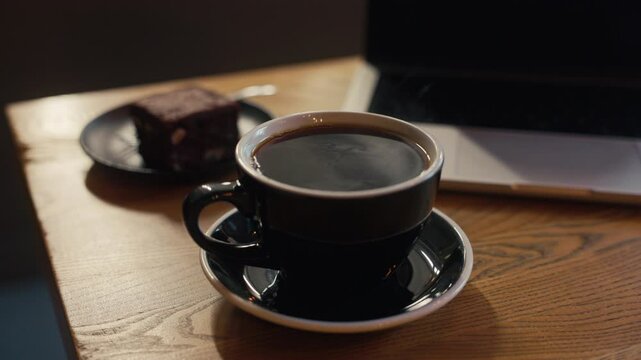 Enjoy a cozy coffee moment with a rich brownie on a rustic table, immersed in a relaxing workspace ambience
