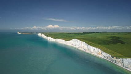 The panorama of the white cliffs of Seven Sisters with clear turquoise water below, East Sussex, England, UK