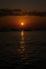 Boats floating on calm water during golden sunset in zanzibar, tanzania