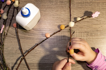 A detailed visual of a crafting activity involving attaching colorful pom-poms to twigs. The image...