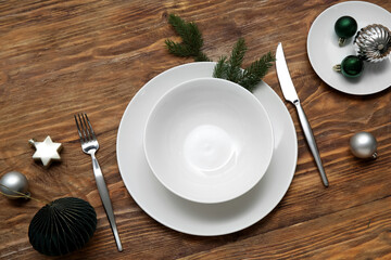 Beautiful table setting with Christmas balls and fir branches on wooden background