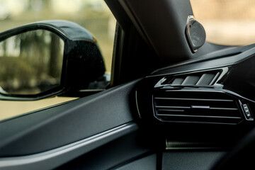 Close-up view of a car's dashboard with air vent and speaker details