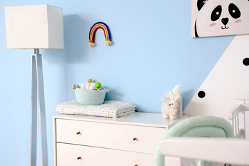 White chest of drawers with baby accessories in room