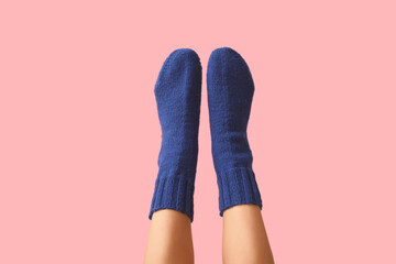Legs of young woman in blue knitted socks on pink background