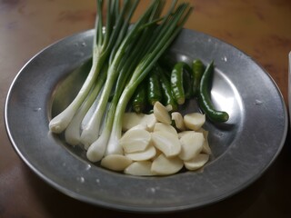 皿に盛り付けられた野菜と薬味（ネギ・ニンニク・唐辛子）