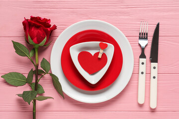 Beautiful table setting with paper heart and red rose on pink wooden background. Valentine's Day celebration