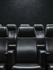 Obraz premium A row of sleek black cinema seats in a dark setting, emphasizing comfort and a modern aesthetic.