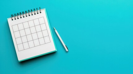 Productivity Tools calendar concept. Blank calendar notebook with a pen on a blue background.