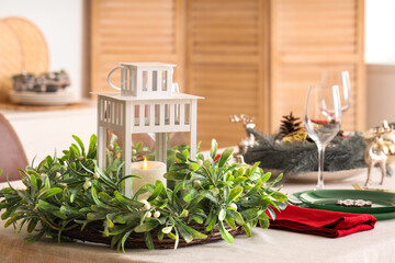 Festive table setting for Christmas dinner with lantern and wreath. Closeup
