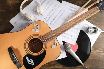 Composition with guitar, microphones, music sheets and headphones on wooden background