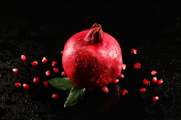Tasty ripe pomegranate and seeds on black background, closeup