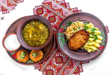 Traditional meal featuring soup, breaded cutlet, and side dishes served on decorative tableware