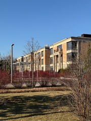 Fototapeta premium modern, multi-story residential buildings with large windows and beige stone facades. The architecture is elegant and contemporary. The weather is clear and sunny, with a bright blue sky
