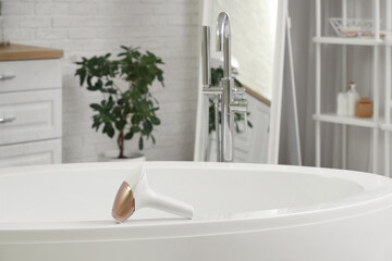 Modern photoepilator on bathtub in bathroom
