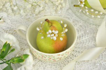 Shallow depth of field, close-up, unusual table decor. In the foreground a pear decorated with pearls. Celebration such as: wedding, arrangement, anniversary, birthday.