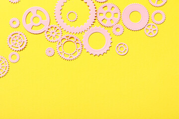 Pink paper gears on yellow background