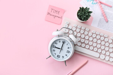 Composition with alarm clock, text TIME MANAGEMENT, computer keyboard and pens on pink background