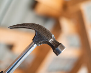 Close up of a hammer, Metal claw hammer against a blurred wood framing.