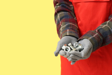 Mechanic with bolts and nuts on yellow background