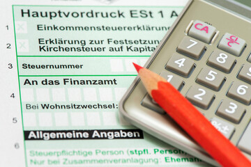 Ein Taschenrechner und ein Rotstift liegen auf einem Formular für die Steuererklärung an das...