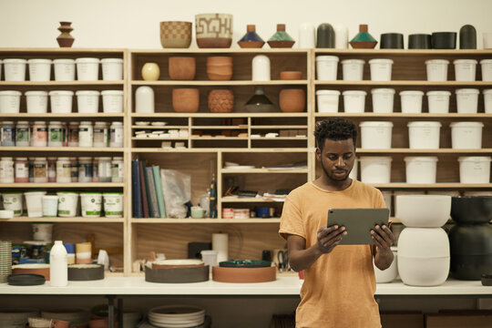 African ceramics workshop manager working on a digital tablet