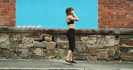 Woman, city and runner with earphones by wall, space and streaming with sound, subscription and...