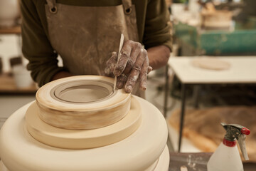 African ceramist shaping clay turning in a mold on a pottery wheel