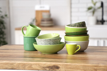 Stacks of bowls and cups on wooden table in kitchen