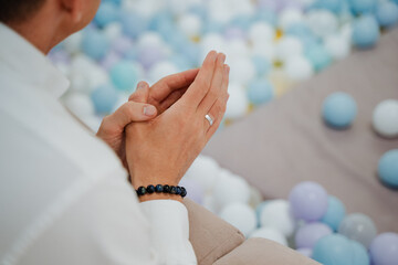 A man sits peacefully on the smooth floor, his hands held together in a prayer position. He...