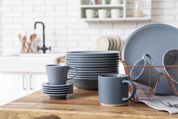 Holder with clean grey dishes on wooden table in kitchen