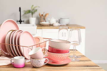 Holder with clean pink dishes on counter in kitchen