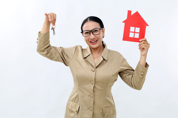 Female hand holding small paper house and keys , posing over white color background wall in studio...