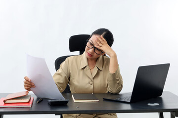 Stressed Female teacher in civil servant uniform with paper and laptop on the desk holding a paper