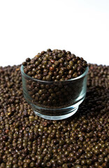 Vertical shot of Organic Black Peas in a Glass Bowl isolated on a white background. Black-eyed peas also called parched peas or dapple peas or Kala Vatana Desi Black Peas.