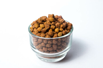 Frontview of Organic Brown Chickpeas in a Glass Bowl Isolated on a white background. Black chickpeas, also known as kala chana, Bengal gram,Egyptian pea.
